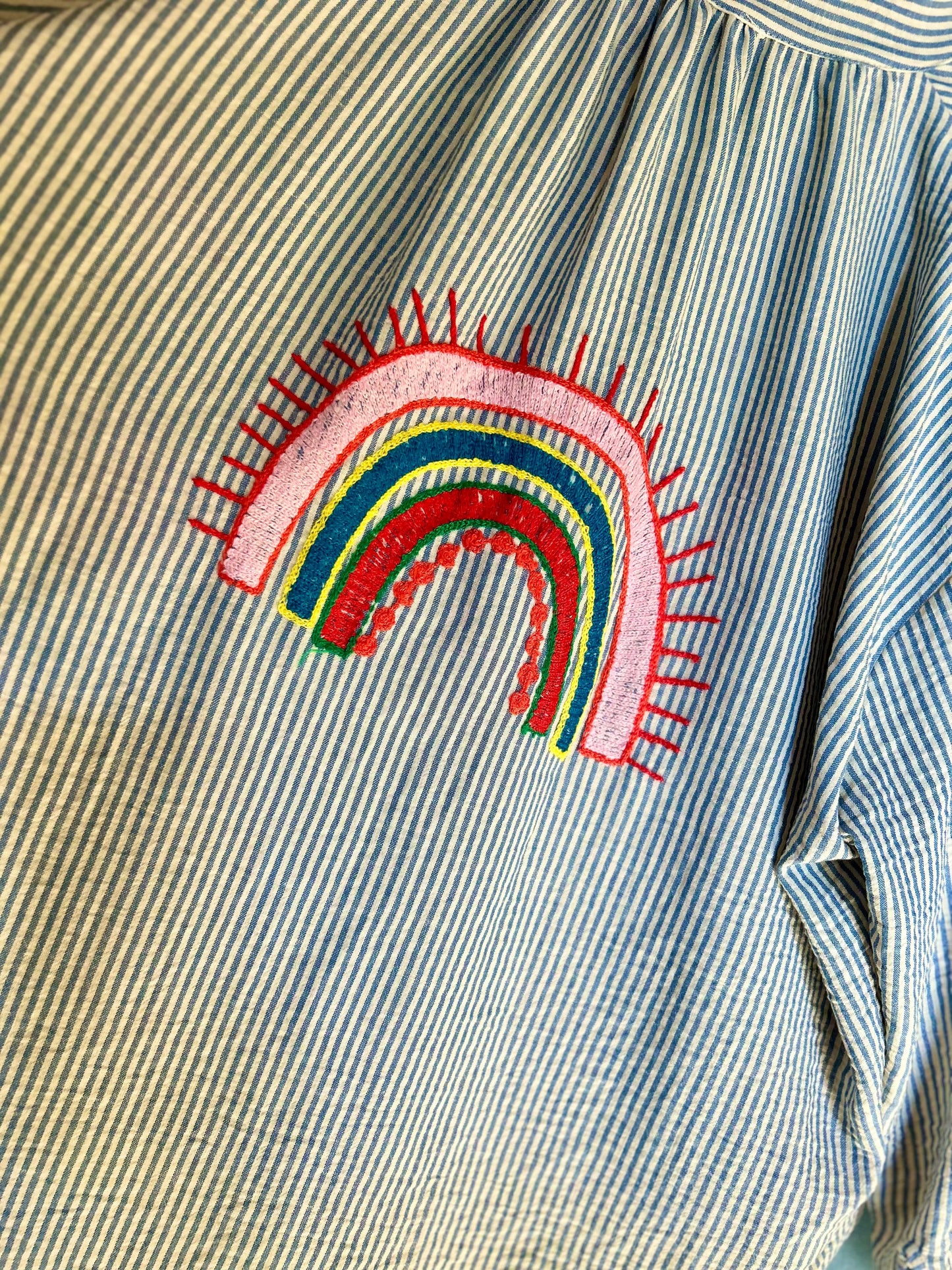 Détail broderie arc-en-ciel sur la blouse Paloma Johanna Paris en coton rayé, pièce unique au style bohème chic et coloré.