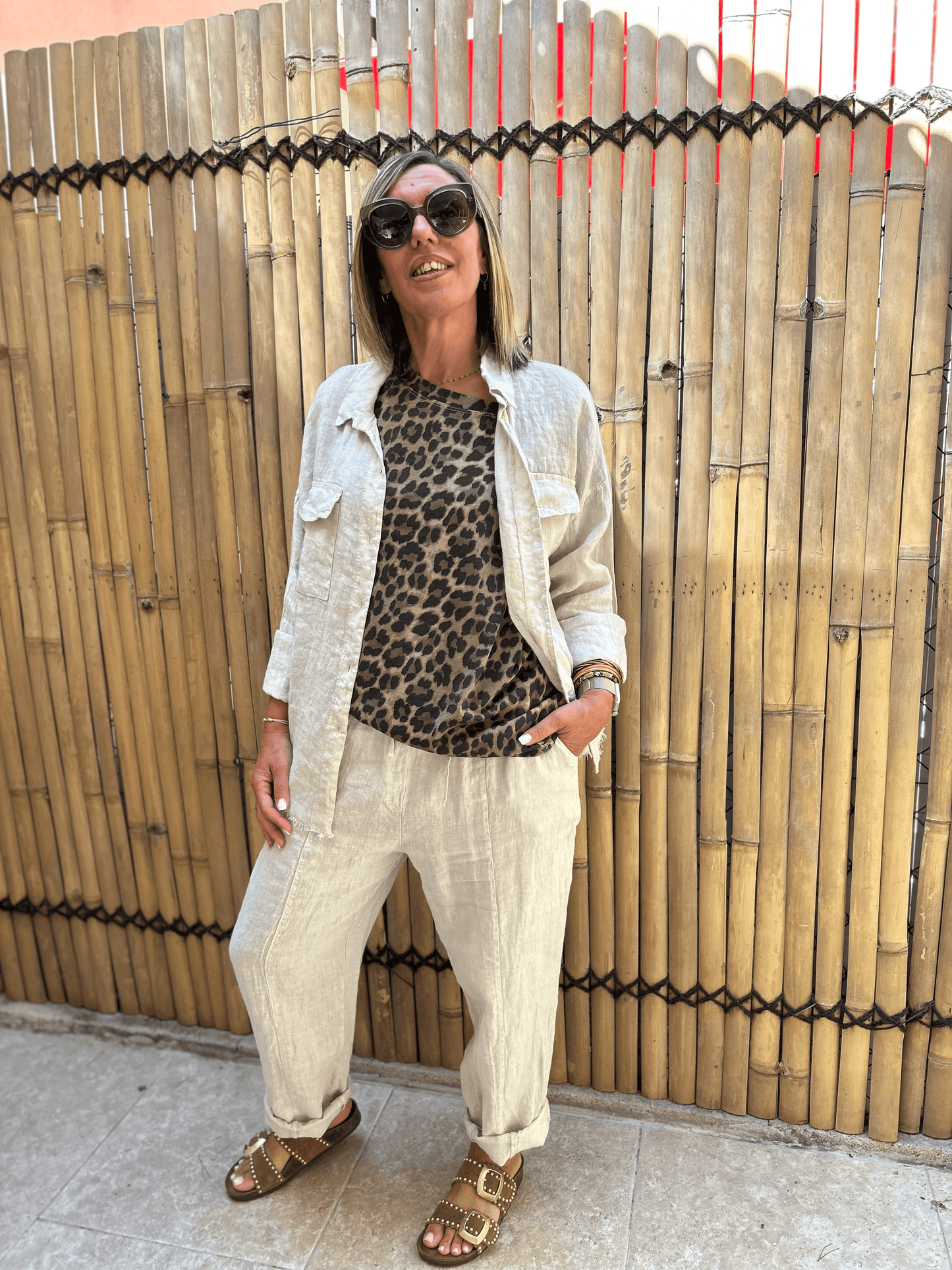 Chemise LUCA beige en lin portée ouverte sur un t-shirt léopard, look féminin casual chic avec pantalon assorti, parfait pour l'été.