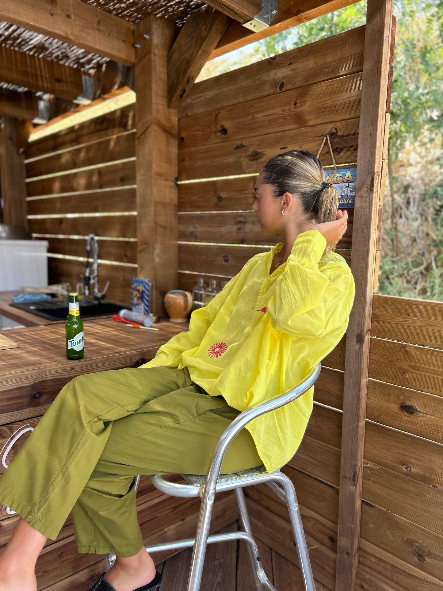 Pantalon Louisa vert olive Johanna Paris, style décontracté et confortable, associé à une chemise jaune brodée, parfait pour un look estival.