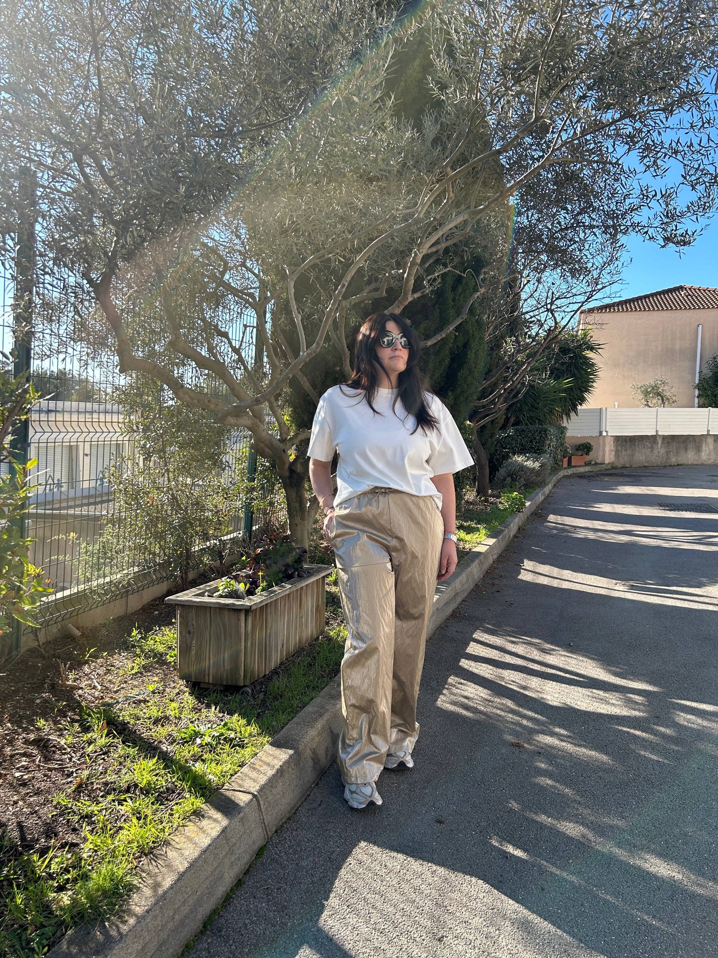 Pantalon large brillant Goldie, revisitant le jogging avec élégance. Son tissu lumineux et sa coupe ample subliment votre silhouette avec style.