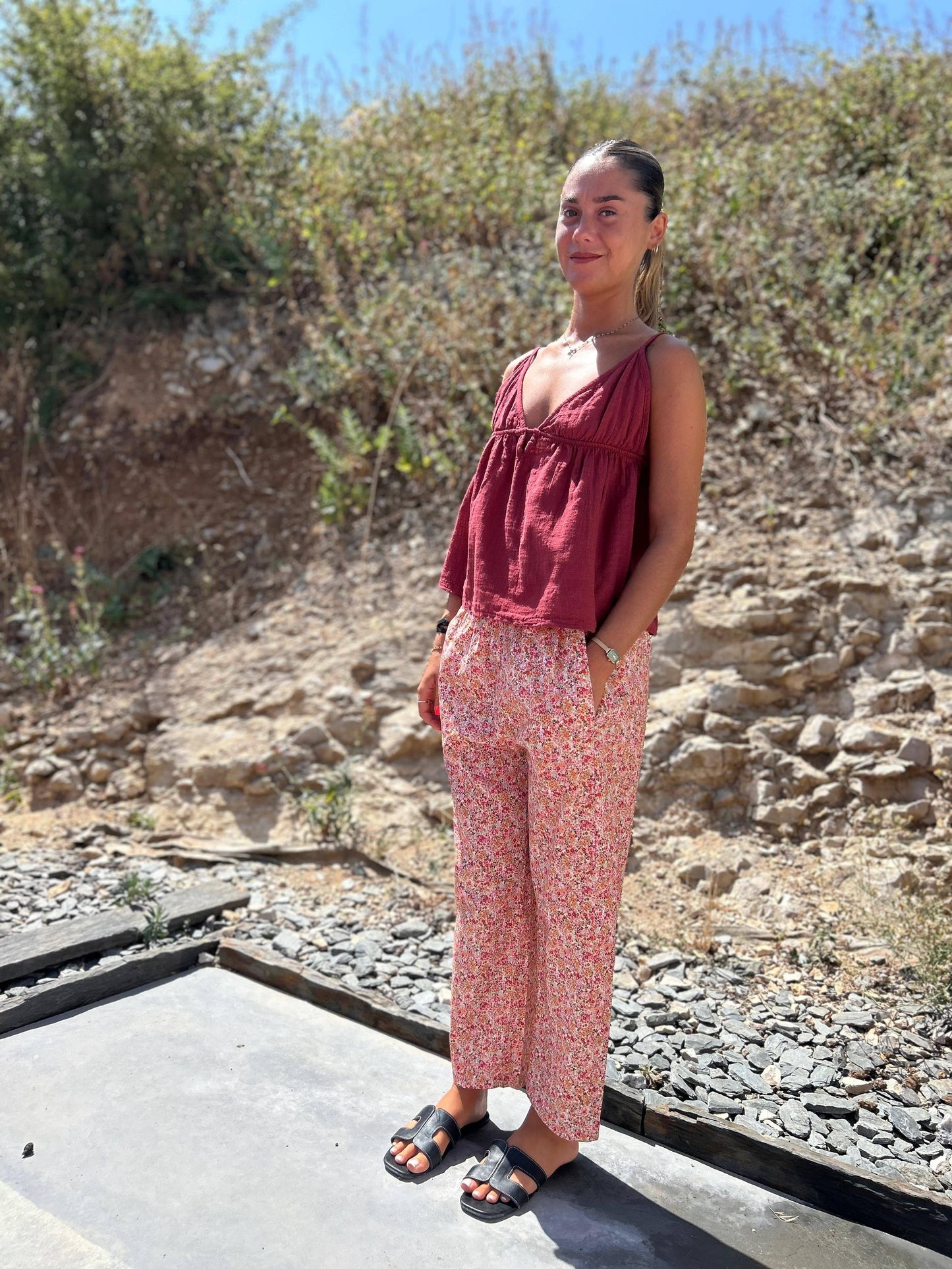 Pantalon Fiora Magic rose à motifs fleuris, porté avec un top bordeaux, style confortable et estival, parfait pour les journées décontractées.