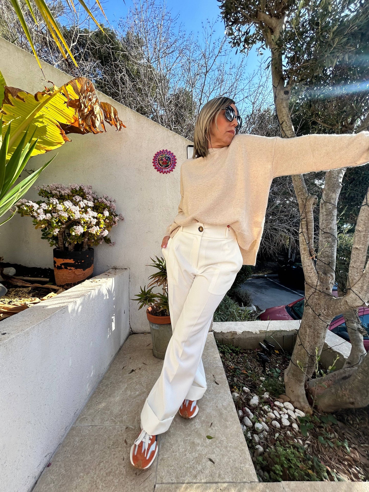 Pull Léa en laine et cachemire beige, coupe ample et col rond, associé à un pantalon blanc. Un look chic et décontracté.