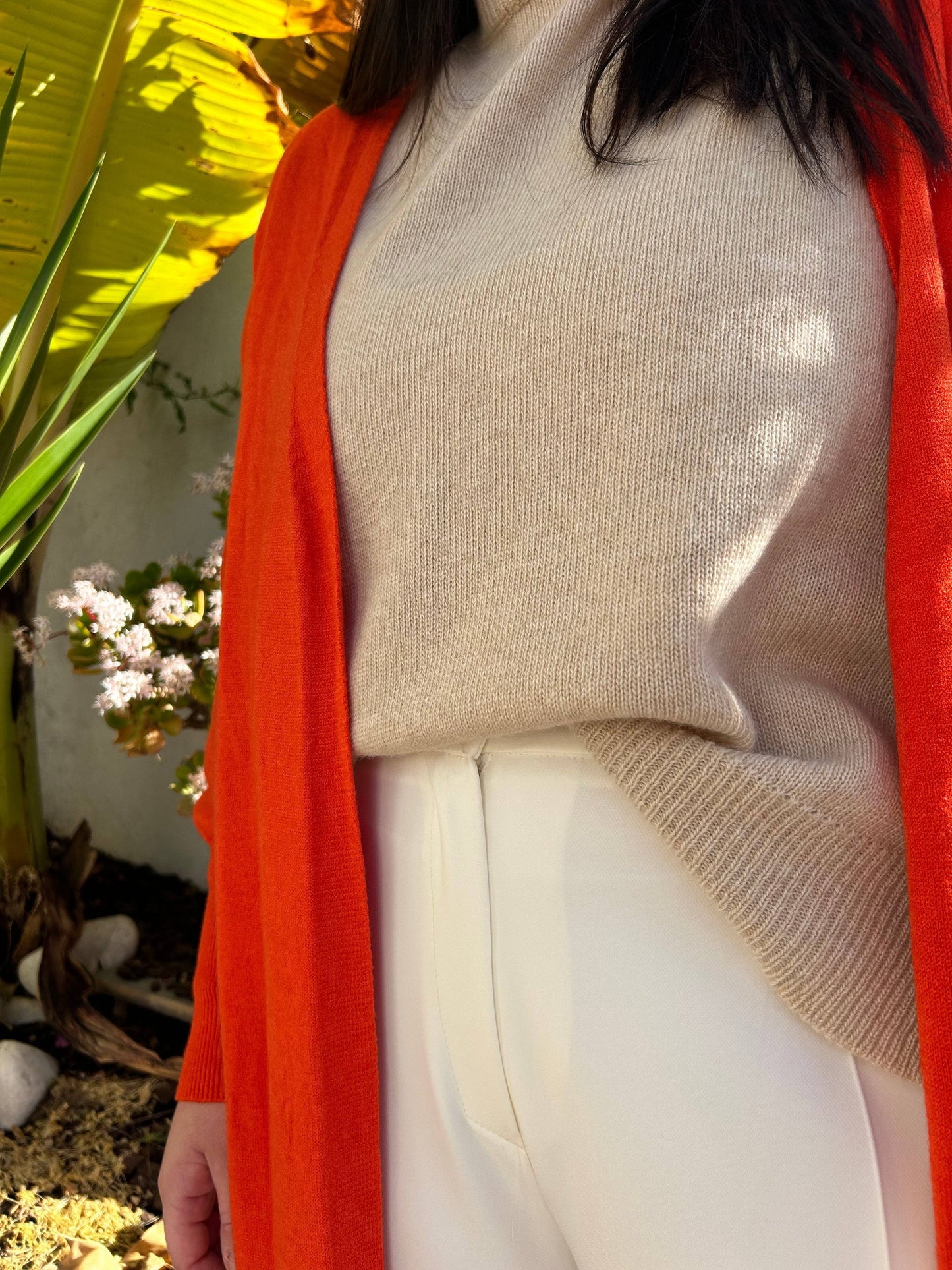 Détail du Pull Léa en maille fine beige, col rond, en laine et cachemire, porté sous un cardigan orange. Élégance et douceur garanties.
