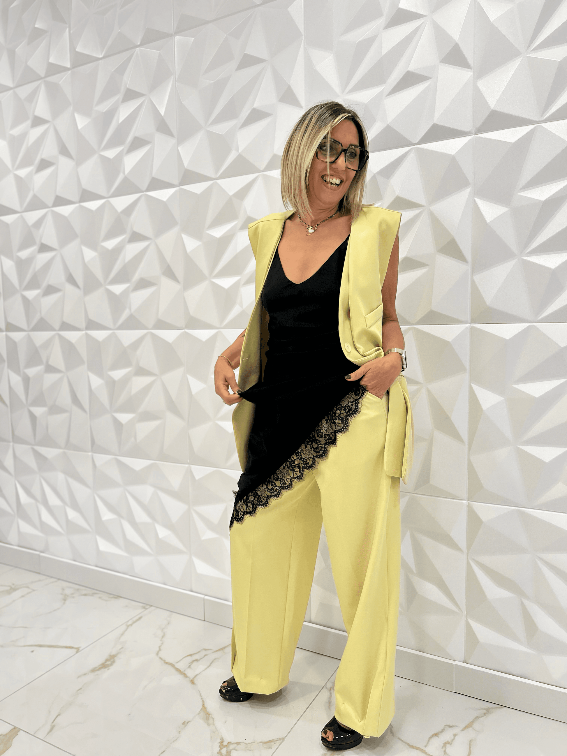 Robe nuisette noire Carmen portée avec un ensemble tailleur jaune, dentelle délicate en finition, tenue élégante et tendance pour femme 2025.