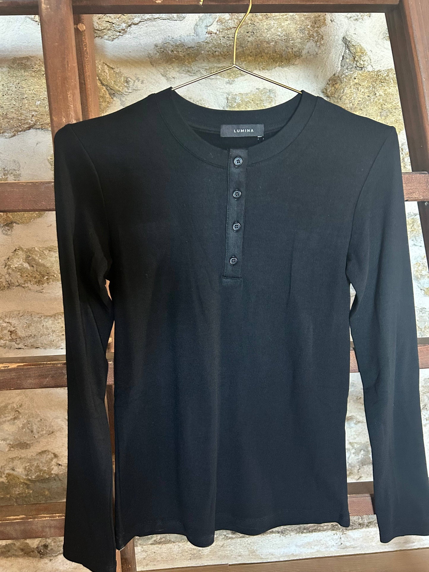 Top Myla noir à manches longues avec col boutonné, coupe près du corps, idéal pour un look chic et confortable automne hiver 2025.