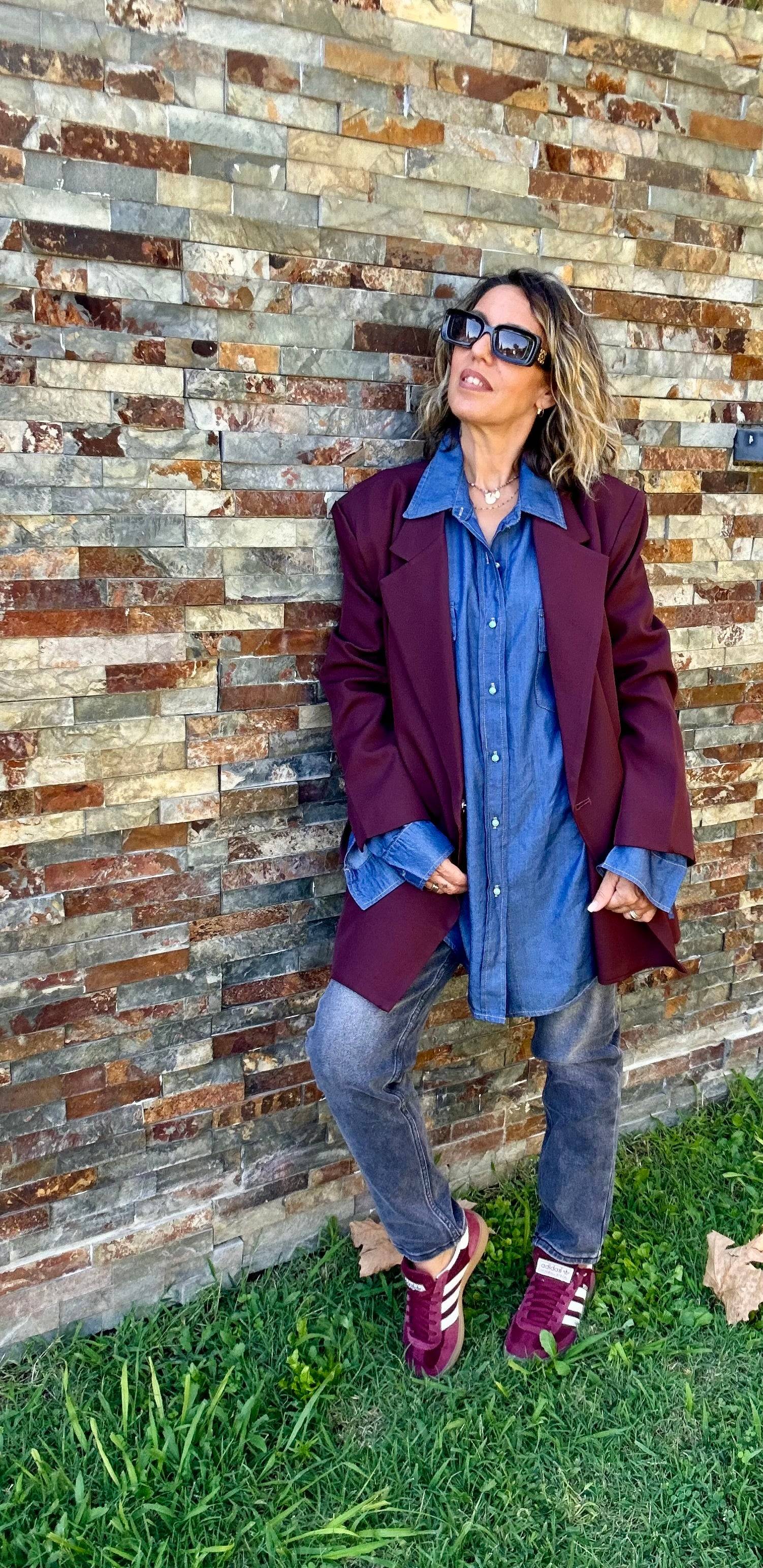 Chemise Denim Clara femme superposée sous une veste bordeaux, style tendance avec jean gris et baskets Adidas bordeaux.