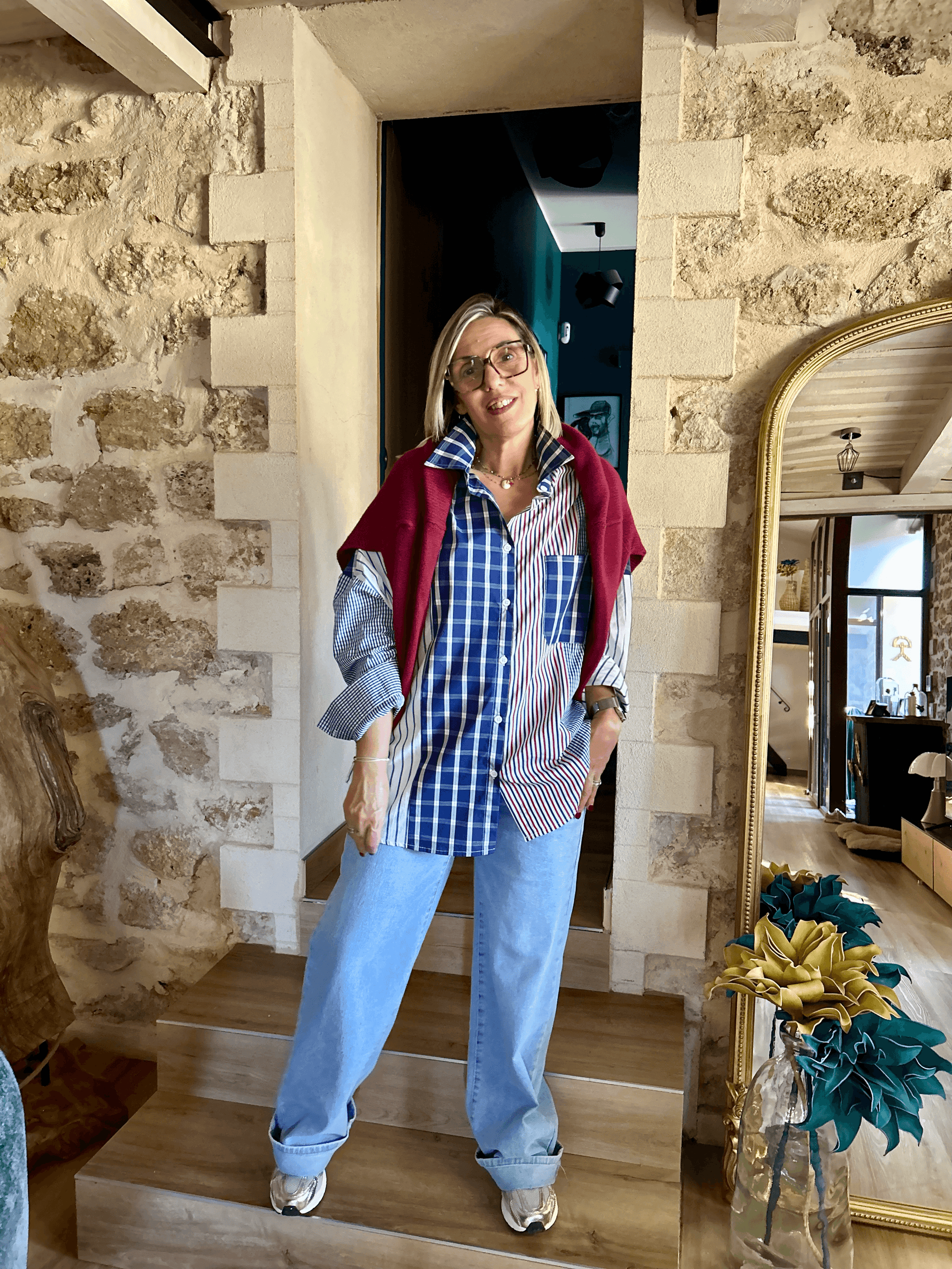 Chemise Alix rayée et à carreaux portée avec pull bordeaux sur les épaules, look urbain automne 2025 pour femme moderne.