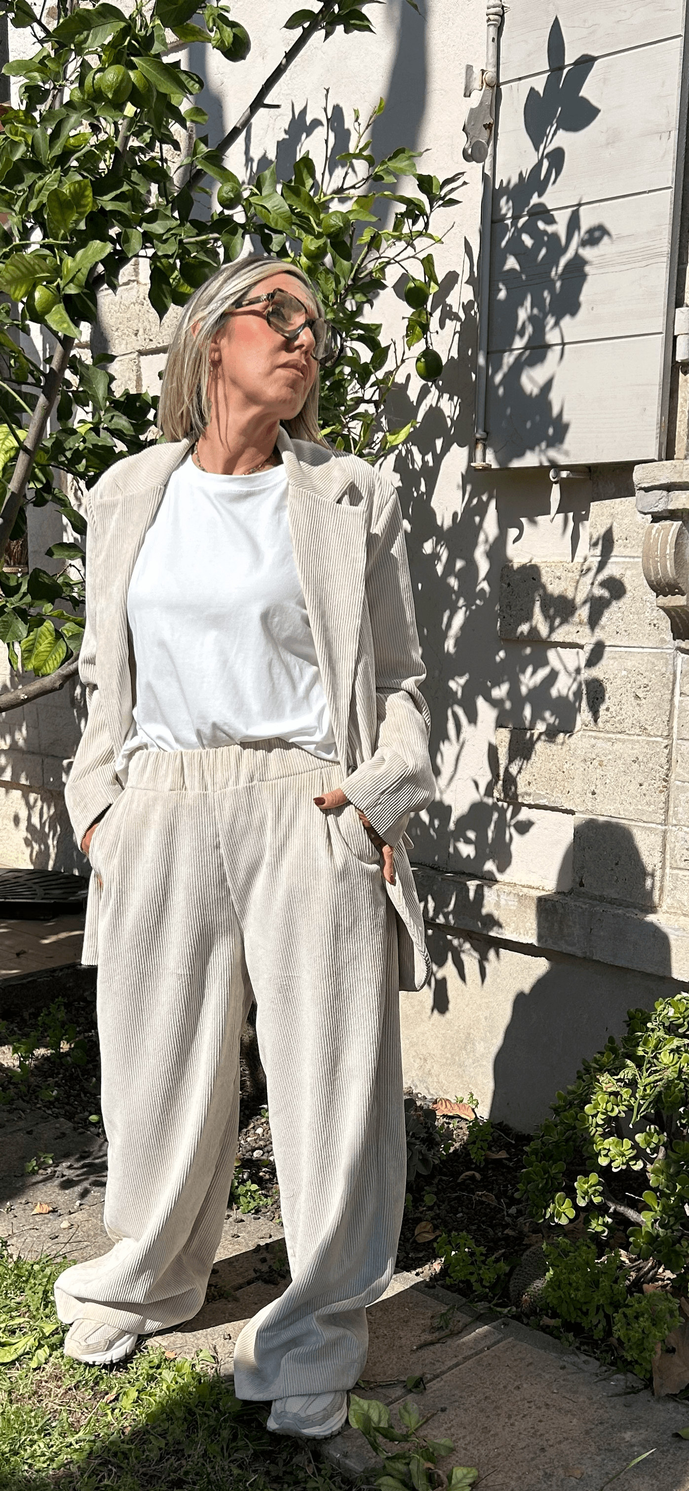 Pantalon Amara large en velours beige, taille élastique, porté avec un blazer coordonné en extérieur, style chic made in Italie.