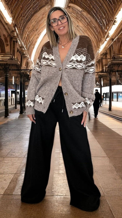 Gilet Jacquard - Aspen doux et oversize, style automne-hiver femme, avec motifs jacquard beige et marron, porté dans une gare historique.