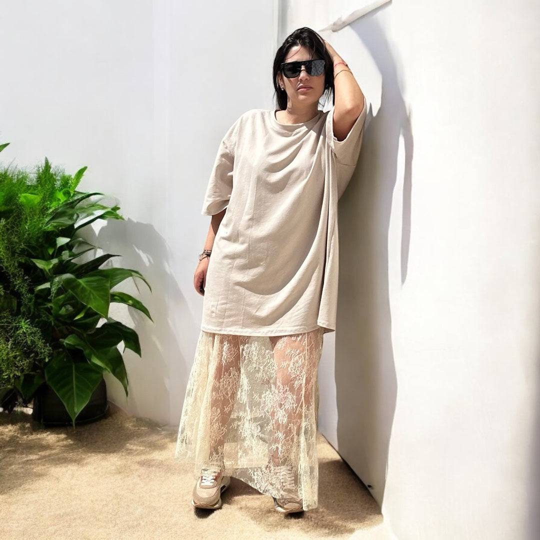 Jupe Diva Boho Chic Lace Maxi Skirt écrue portée avec un t-shirt ample beige et baskets, look bohème chic et décontracté pour l'été 2025.
