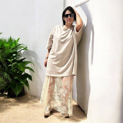 Jupe Diva Boho Chic Lace Maxi Skirt écrue portée avec un t-shirt ample beige et baskets, look bohème chic et décontracté pour l'été 2025.