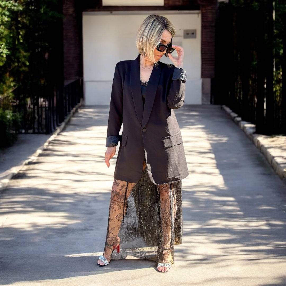 Jupe Diva Boho Chic Lace Maxi Skirt noire en dentelle portée avec un blazer noir, style féminin et tendance pour l'été 2025.