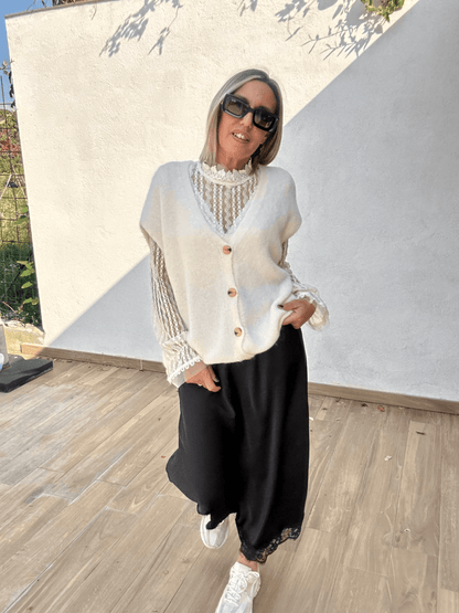 Jupe noire satinée Ziggy fluide et élégante avec dentelle, associée à un gilet blanc sans manches et un haut en dentelle, style tendance automne-hiver 2025.