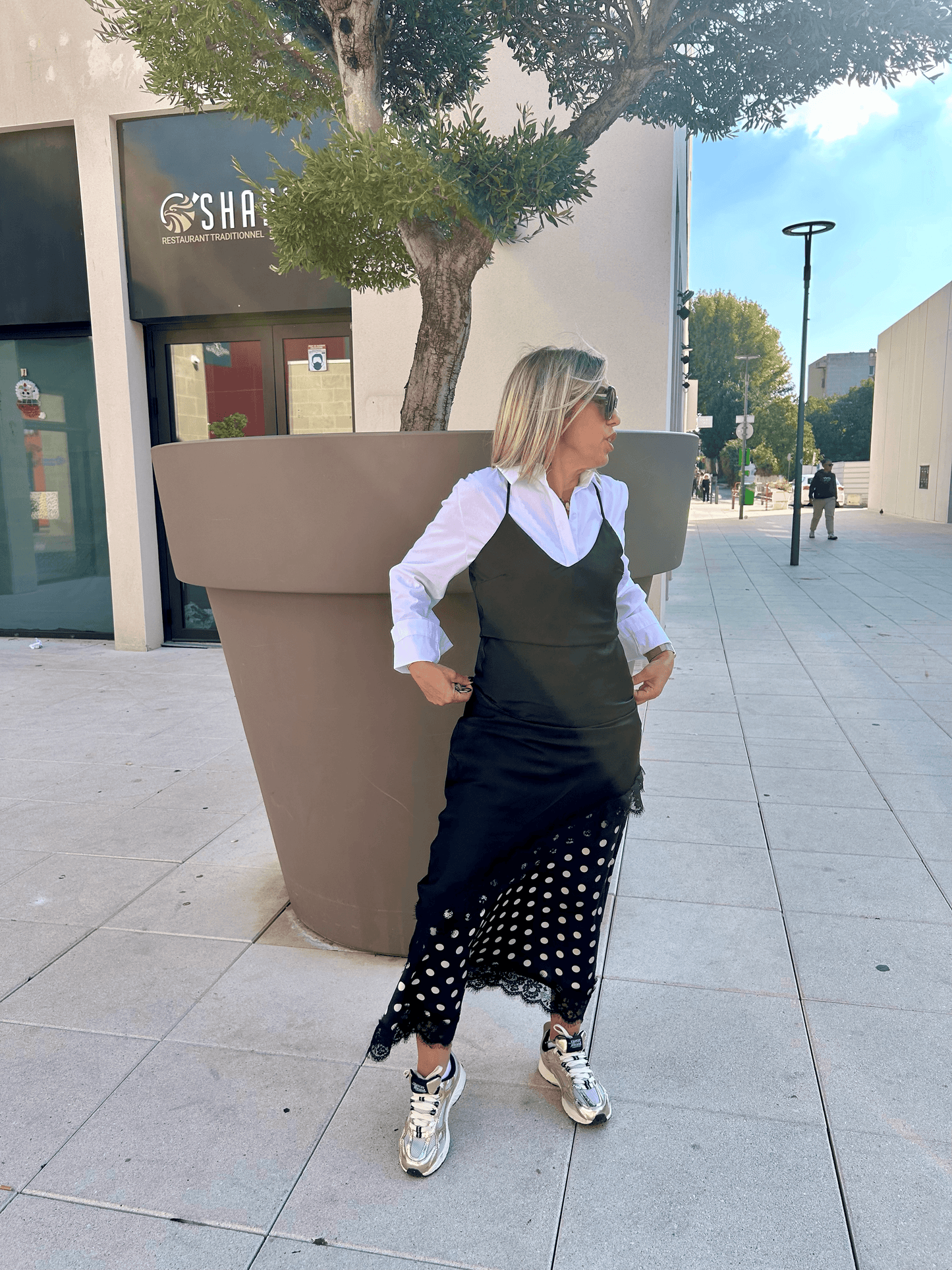 Jupe satinée à pois Stella portée avec une chemise blanche et robe noire superposée, look tendance et élégant de Vestiaire du Sud.