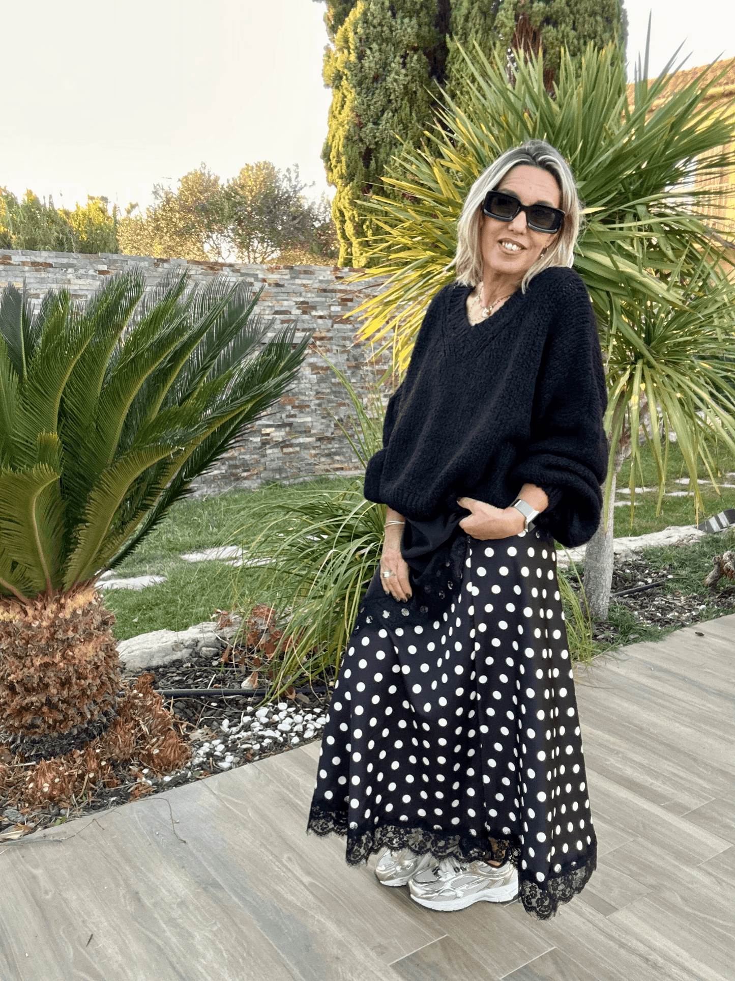 Jupe satinée à pois Stella noire avec dentelle portée avec un pull oversize noir, look féminin et élégant signé Vestiaire du Sud.