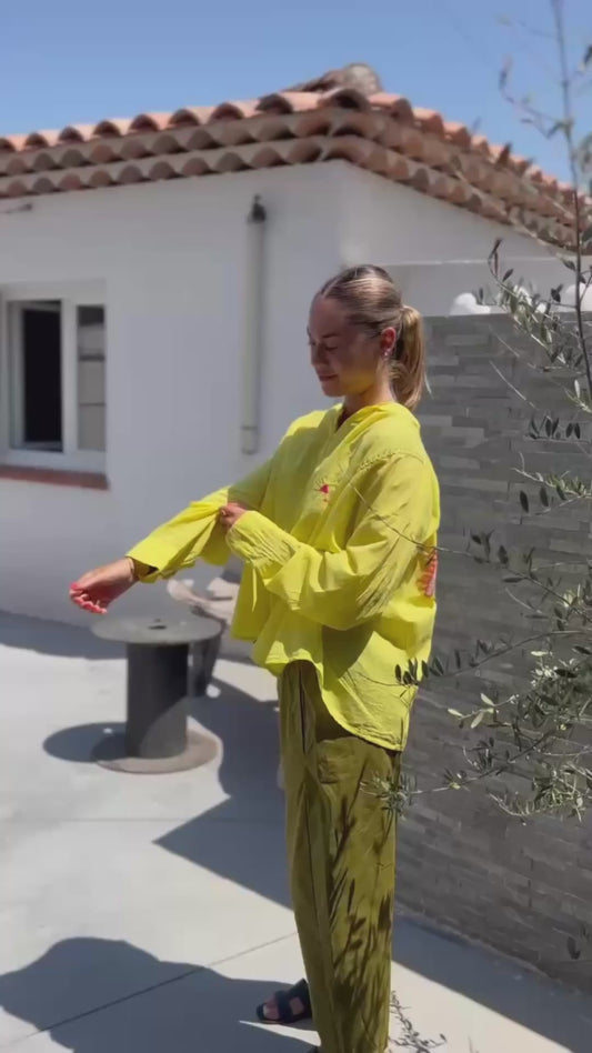 Pantalon Magique Louisa vert olive de Johanna Paris porté avec une chemise jaune, coupe ample et taille élastique pour un confort optimal.