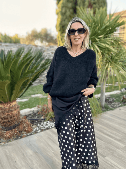 Gabriel Black V-Neck Sweater pour femme, associé à une jupe fluide à pois, parfait pour une tenue élégante et confortable en automne-hiver.