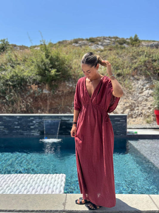 Robe Amaya - Johanna Paris en coton brique, coupe fluide et taille unique, portée au bord d'une piscine, idéale pour l'été 2025.