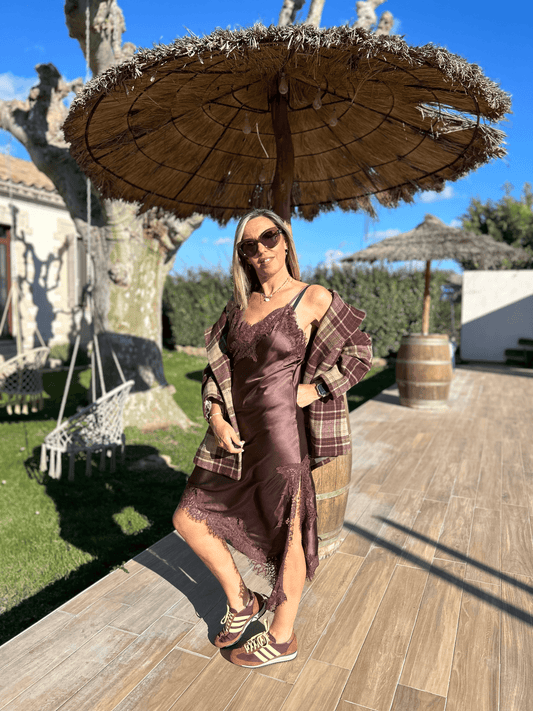 Robe asymétrique satinée chocolat Luna chic & tendance avec dentelle, portée avec une veste à carreaux et baskets pour un look décontracté élégant.