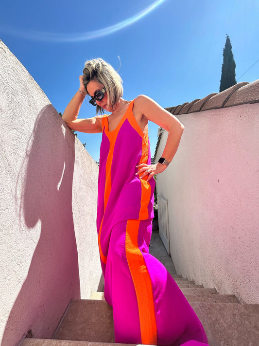 Robe Summer Vibes fluide à col V, sans manches, rose fuchsia et orange, portée en extérieur sous un ciel bleu, idéale pour l'été 2025.