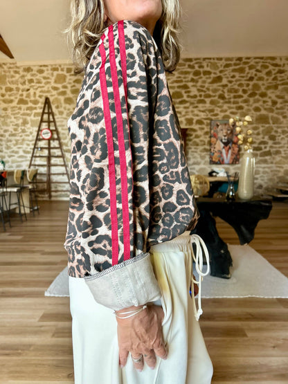 Zoom sur le sweat léopard Savanna demi-saison, mettant en valeur les bandes rouges contrastantes sur les manches et le tissu à imprimé animalier.
