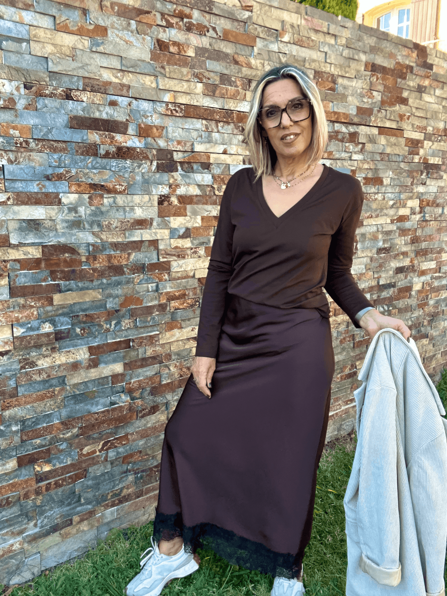 Top manches longues chocolat Paula avec col V, associé à une jupe longue, style basique chic idéal pour la mode femme automne-hiver 2025.